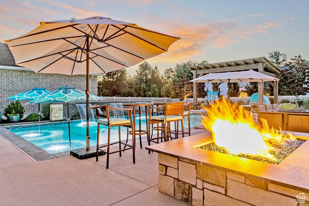 Pool at dusk with a patio and a fire pit