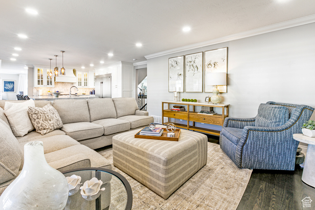 Living room featuring sink, crown molding, and hardwood / wood-style floors