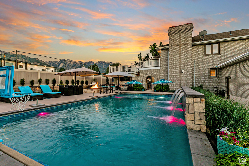 Pool at dusk with pool water feature and a patio area