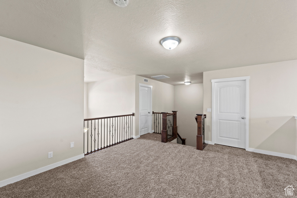 Carpeted spare room with a textured ceiling