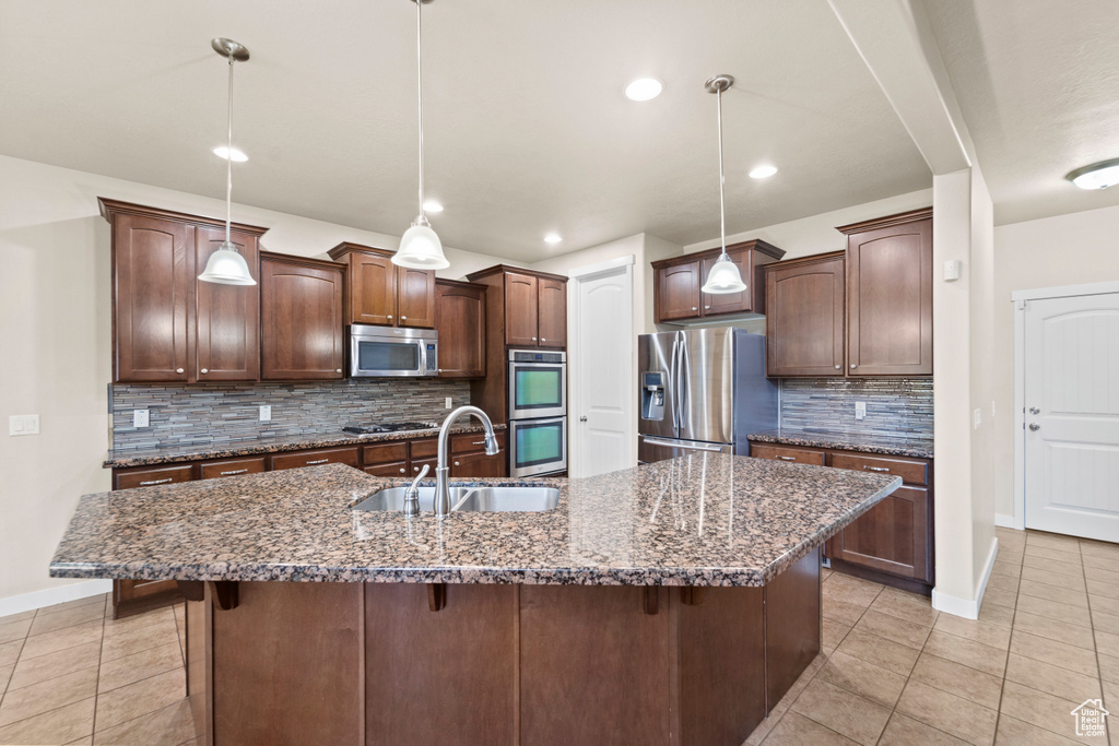 Kitchen featuring sink, a kitchen island with sink, tasteful backsplash, and stainless steel appliances