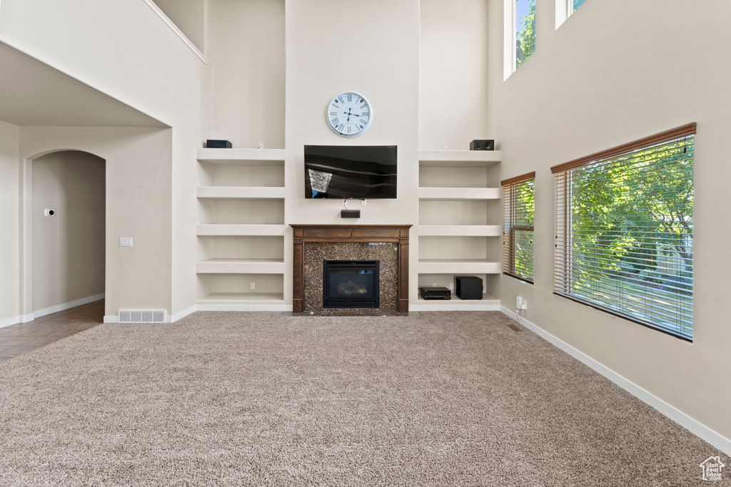 Unfurnished living room featuring built in features, a fireplace, and a healthy amount of sunlight