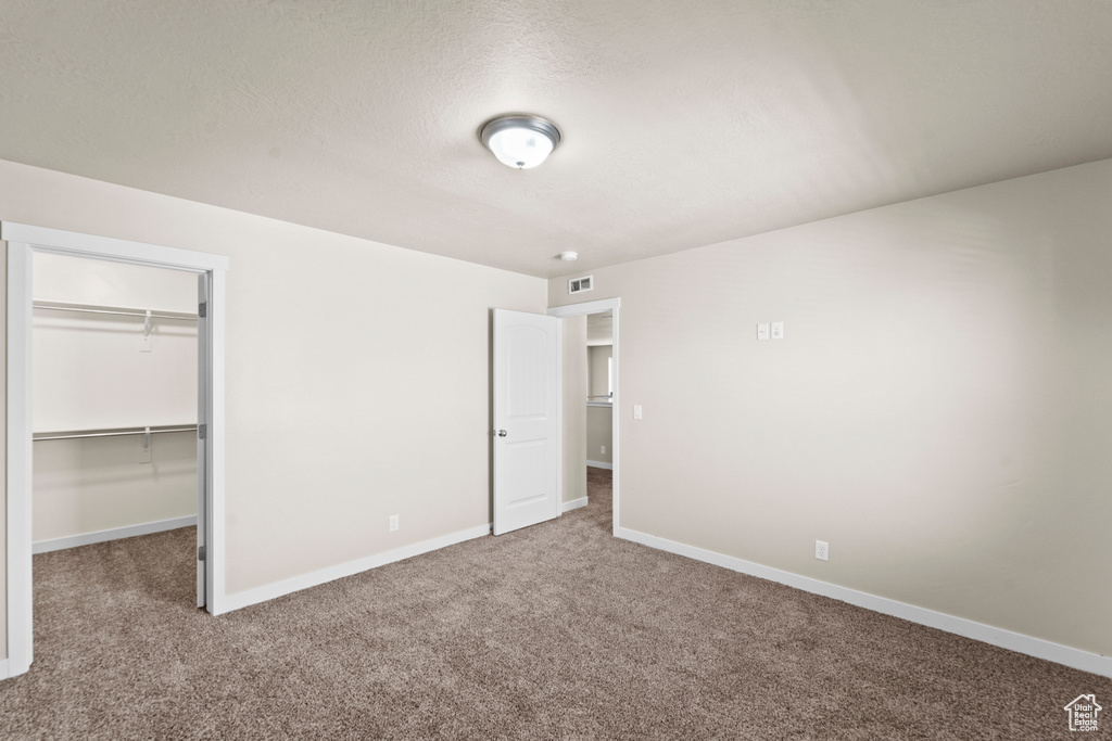 Unfurnished bedroom with a spacious closet, a closet, and carpet flooring