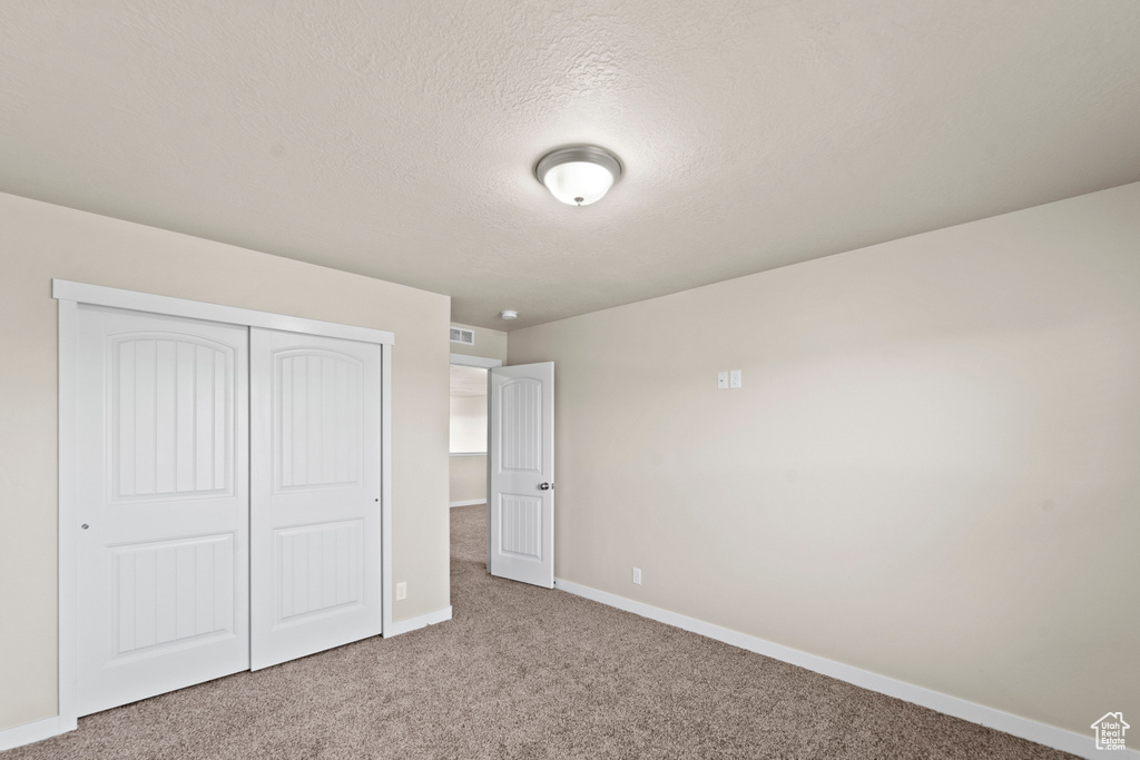 Unfurnished bedroom featuring a closet and carpet flooring