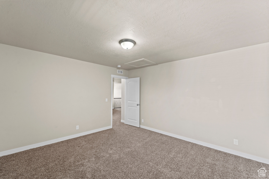 Empty room featuring carpet flooring and a textured ceiling