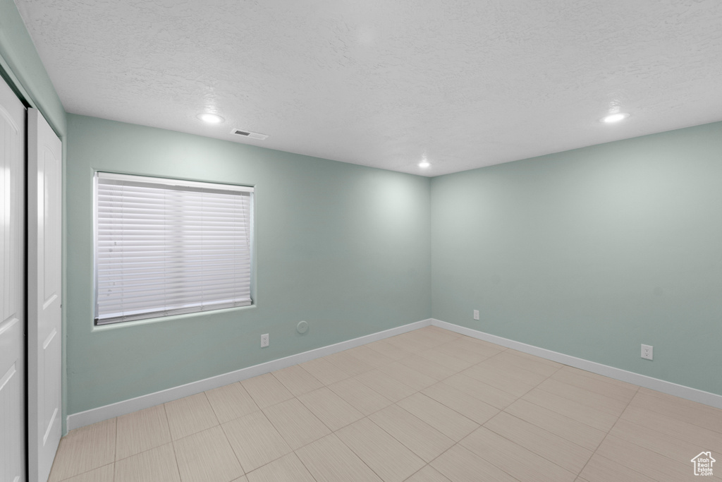 Tiled spare room featuring a textured ceiling