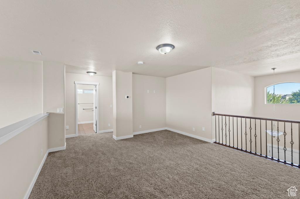 Empty room with carpet and a textured ceiling