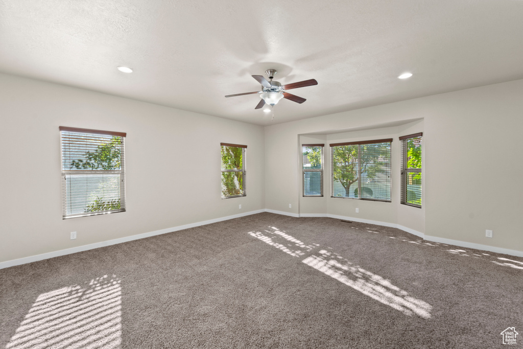 Carpeted empty room with plenty of natural light and ceiling fan