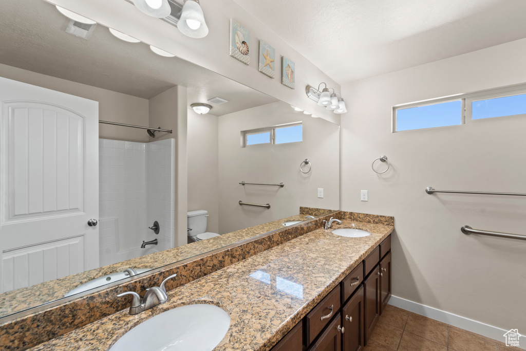 Full bathroom with plenty of natural light, tile patterned floors, toilet, and dual bowl vanity