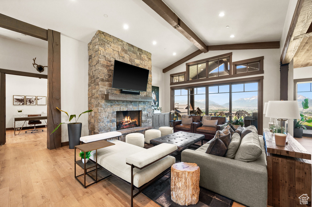 Living room with light hardwood / wood-style flooring, beam ceiling, high vaulted ceiling, and a fireplace