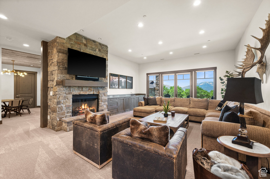 Carpeted living room featuring a chandelier and a stone fireplace