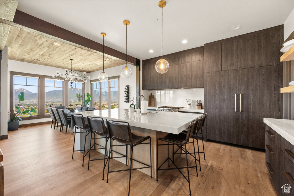 Kitchen with a mountain view, hanging light fixtures, a center island with sink, and light wood-type flooring