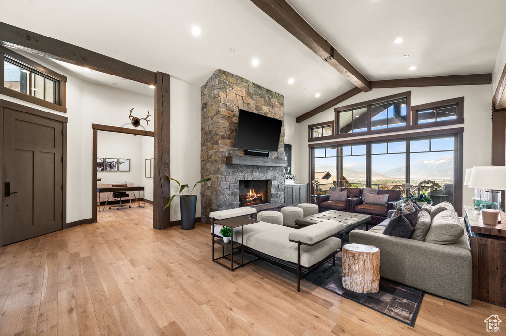 Living room featuring a fireplace, light hardwood / wood-style flooring, beamed ceiling, and high vaulted ceiling