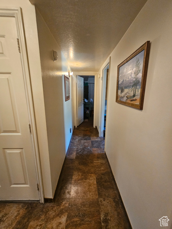 Corridor with a textured ceiling and dark tile patterned flooring