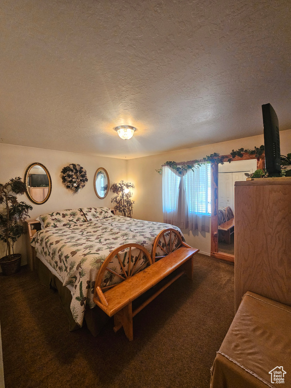 Bedroom featuring dark carpet and a textured ceiling