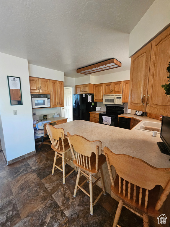 Kitchen featuring dark tile patterned flooring, black appliances, and sink