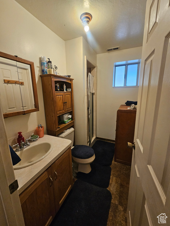 Bathroom featuring vanity, tile patterned floors, walk in shower, and toilet