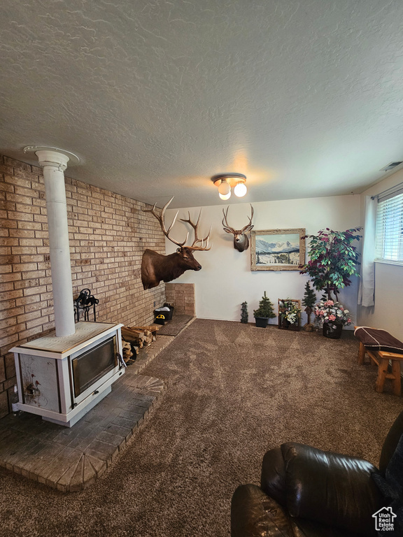 Unfurnished living room featuring dark colored carpet, a textured ceiling, ornate columns, and a wood stove