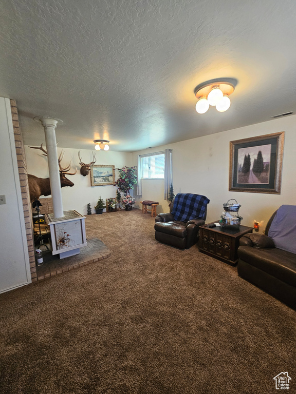 Living room with brick wall, ornate columns, carpet flooring, and a textured ceiling