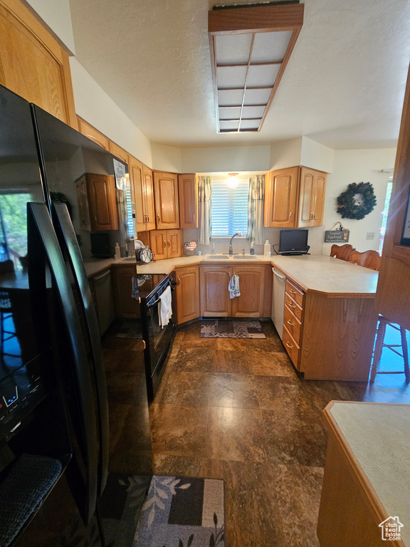 Kitchen featuring black appliances, sink, and dark tile patterned flooring