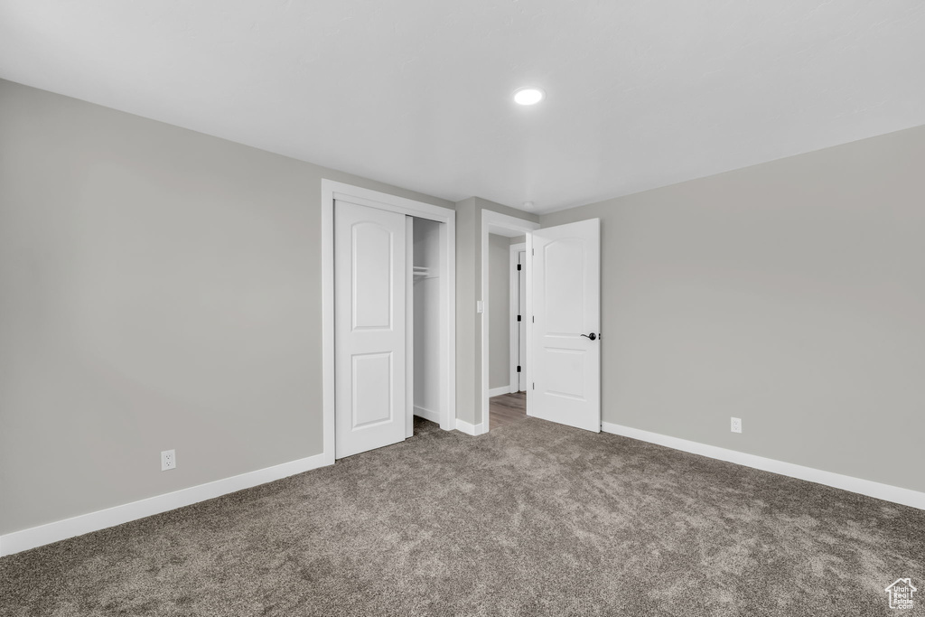 Unfurnished bedroom with dark carpet and a closet