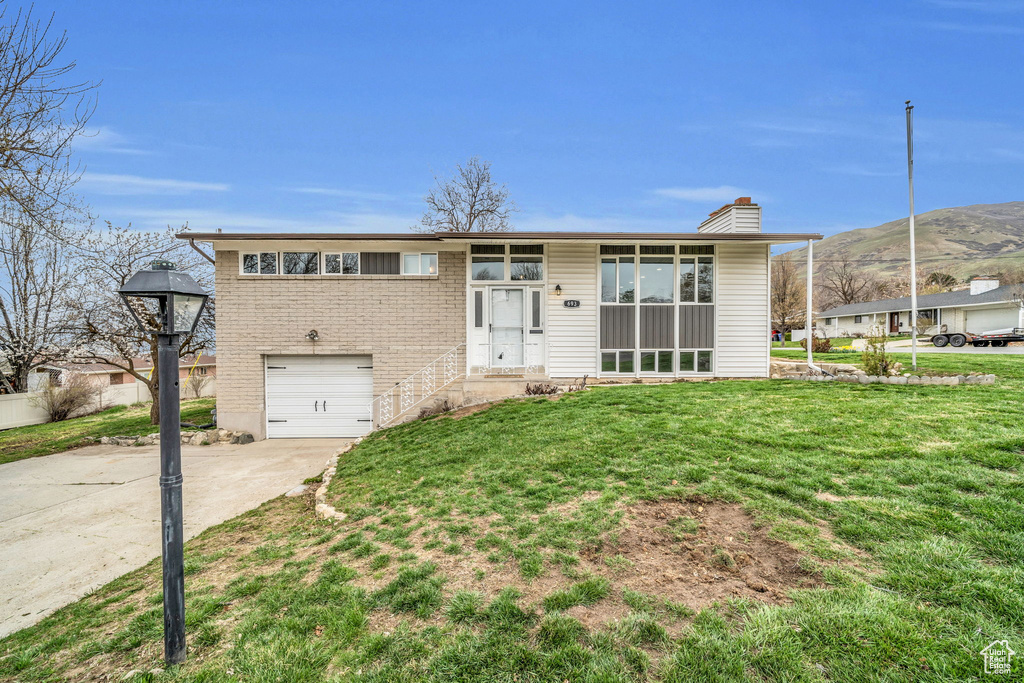 View of front facade with a garage, a mountain view, and a front lawn