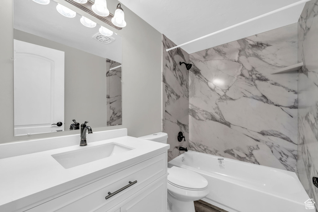 Full bathroom featuring vanity, tiled shower / bath combo, and toilet