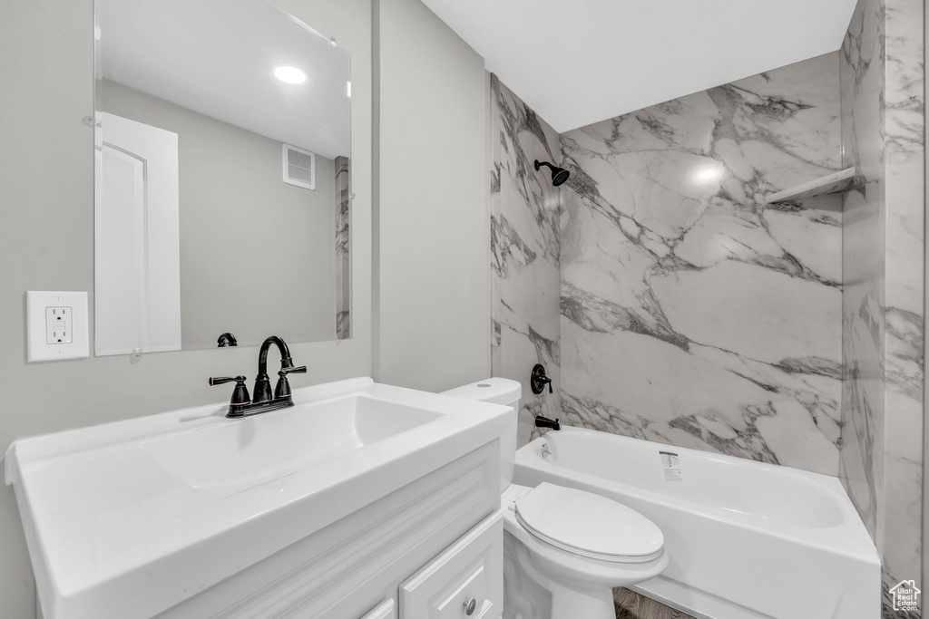 Full bathroom featuring vanity, tiled shower / bath combo, and toilet