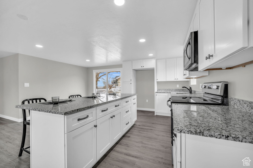 Kitchen featuring a kitchen island, appliances with stainless steel finishes, light wood-type flooring, and white cabinets