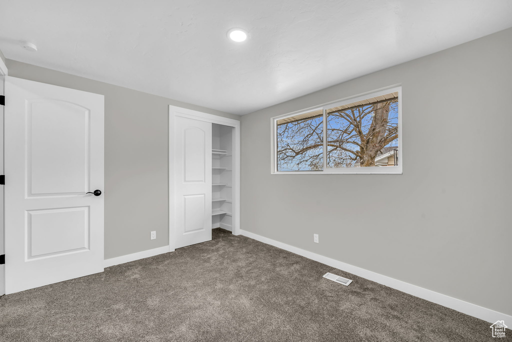 Unfurnished bedroom with dark carpet and a closet