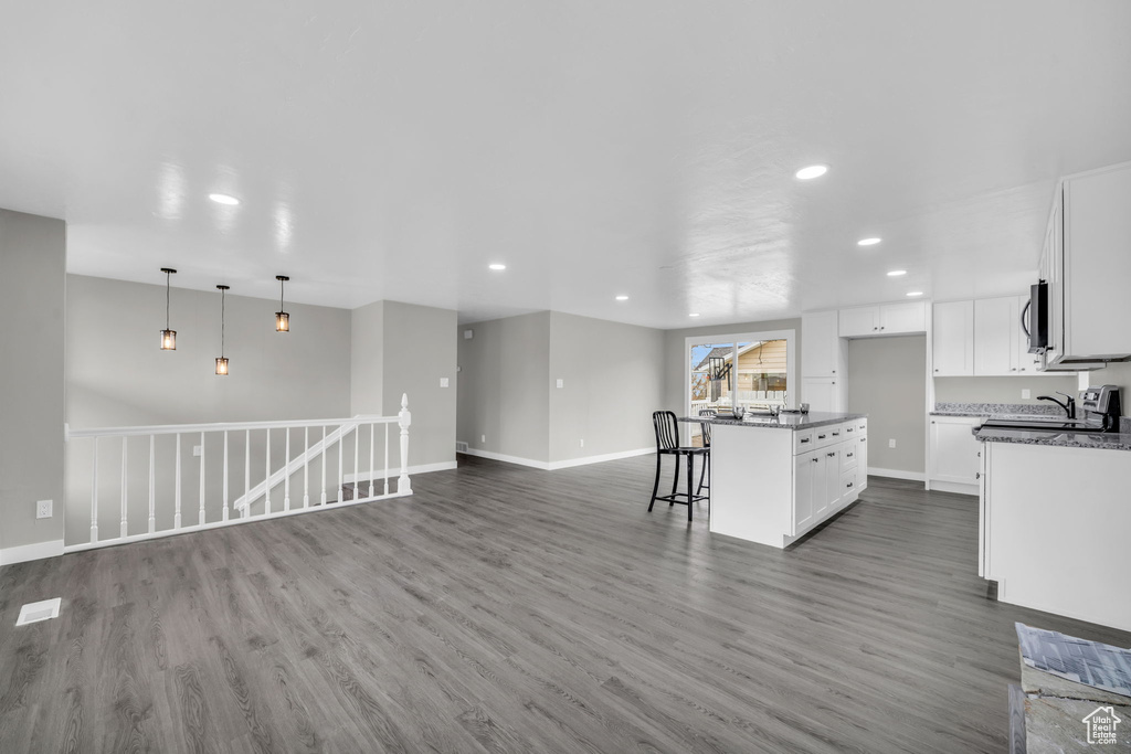 Kitchen featuring white cabinetry, hardwood / wood-style flooring, decorative light fixtures, and a center island