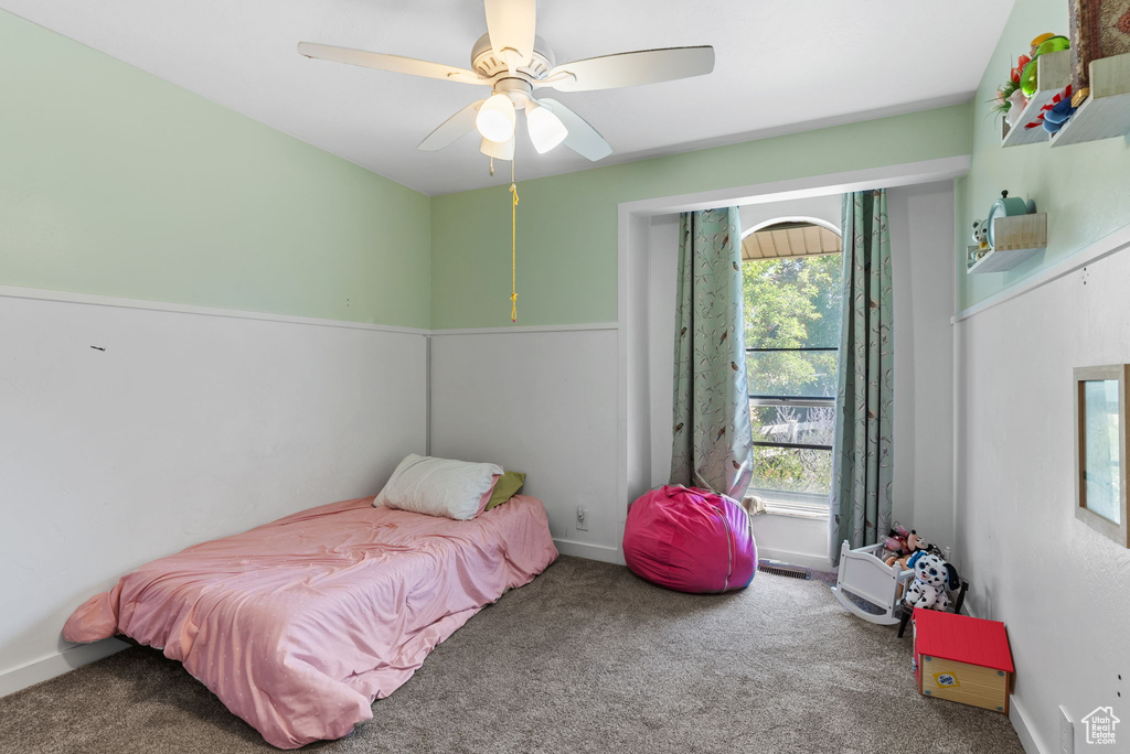 Carpeted bedroom with multiple windows and ceiling fan