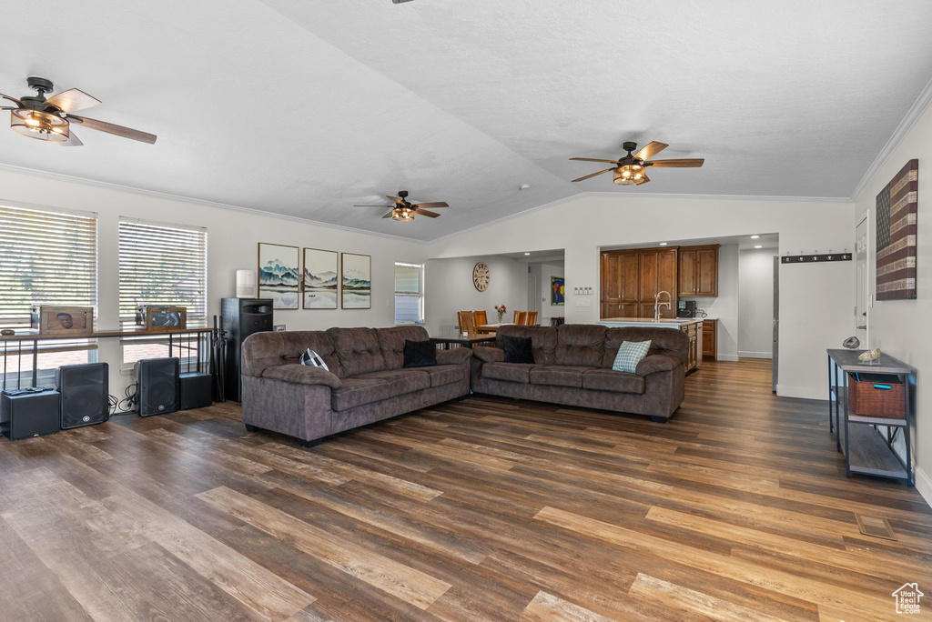 Living room with ceiling fan, crown molding, dark hardwood / wood-style flooring, and vaulted ceiling