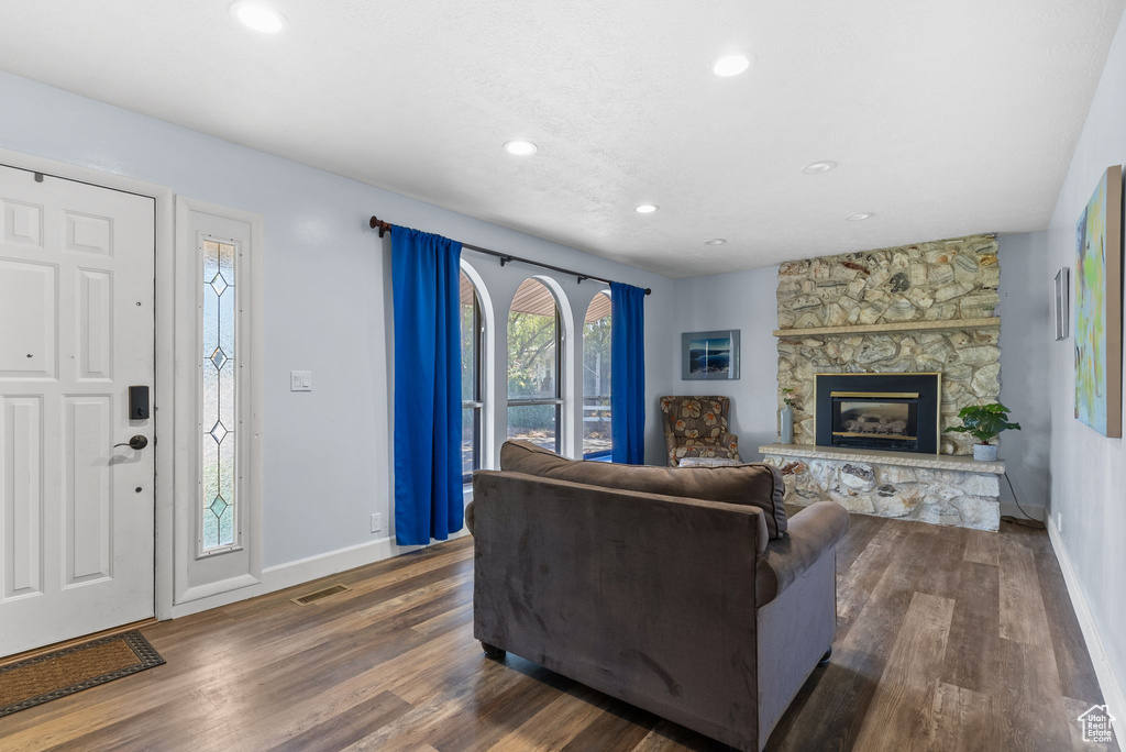 Living room featuring a stone fireplace and dark hardwood / wood-style flooring