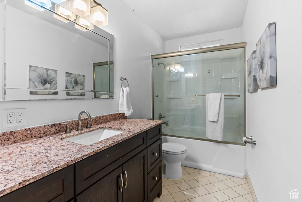 Full bathroom featuring vanity, tile patterned floors, combined bath / shower with glass door, and toilet