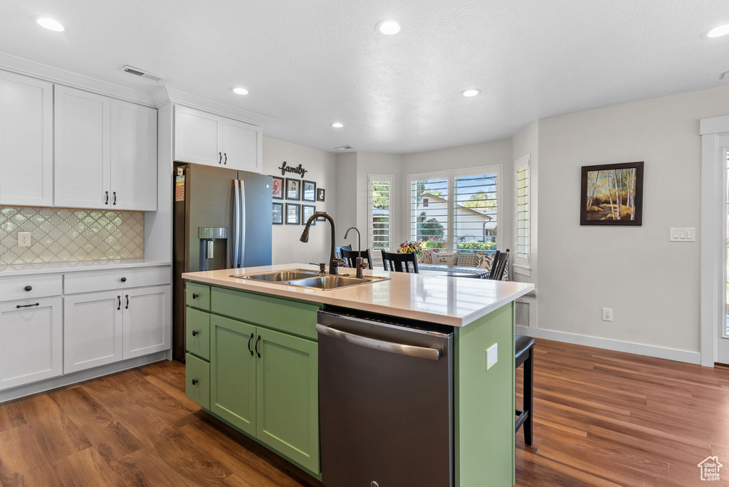 Kitchen with appliances with stainless steel finishes, dark hardwood / wood-style floors, a center island with sink, and white cabinetry