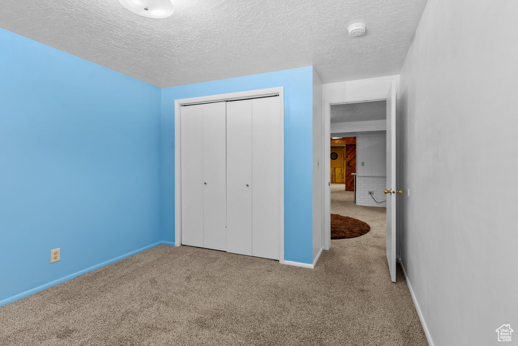 Unfurnished bedroom with carpet flooring, a closet, and a textured ceiling