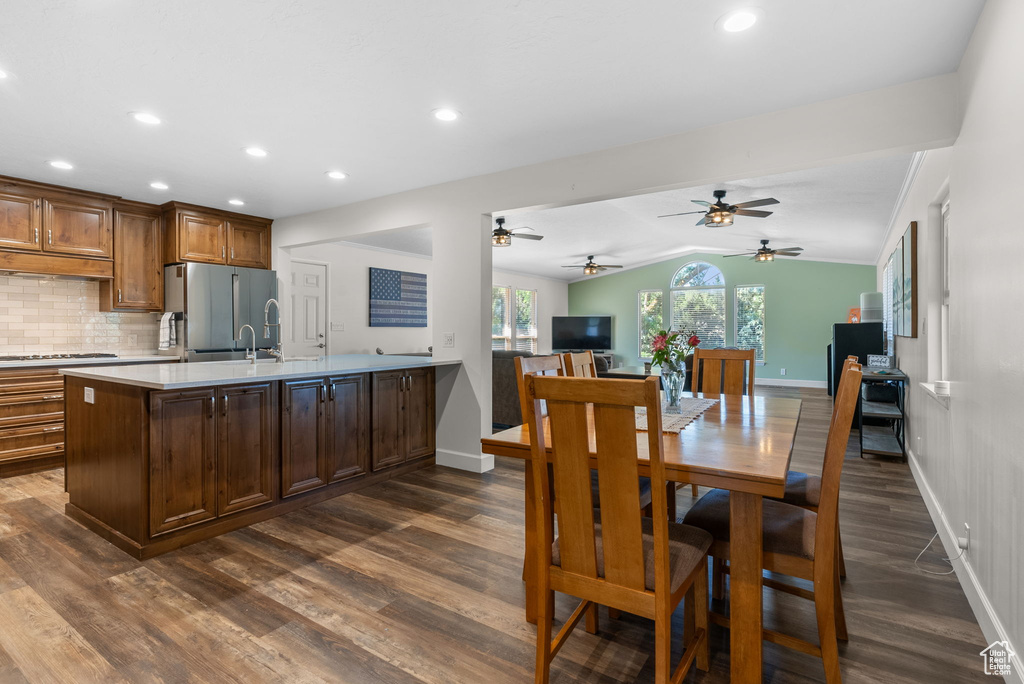 Interior space with stainless steel refrigerator, gas stovetop, dark hardwood / wood-style flooring, ceiling fan, and decorative backsplash