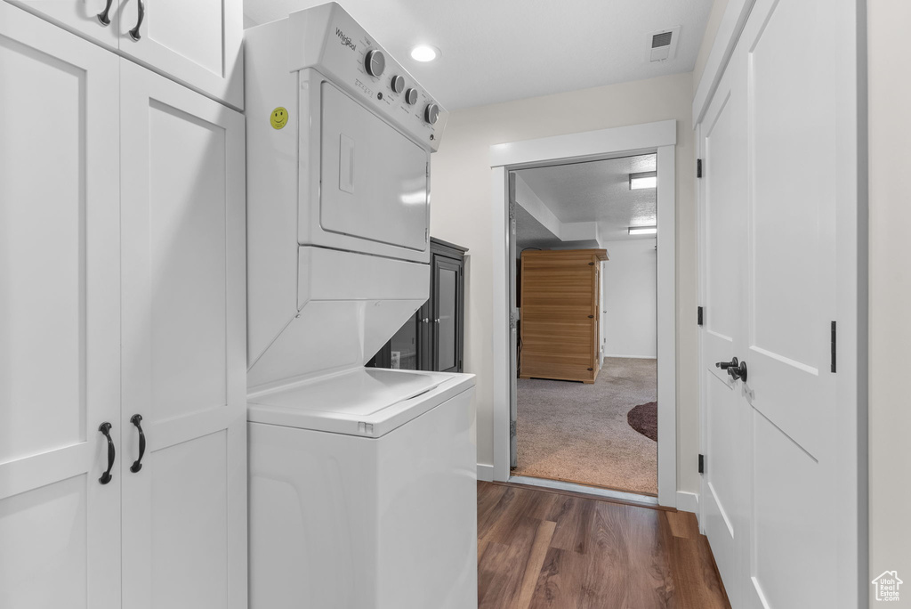 Clothes washing area with stacked washer / dryer and dark wood-type flooring