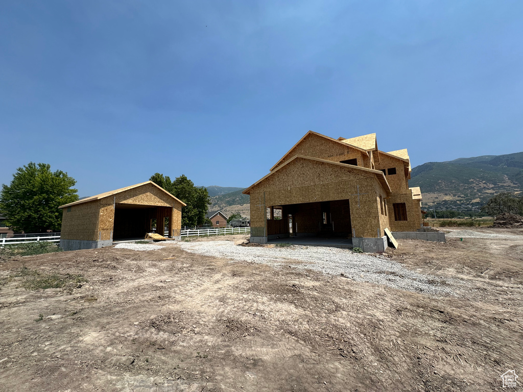 View of side of property with a mountain view and an outbuilding