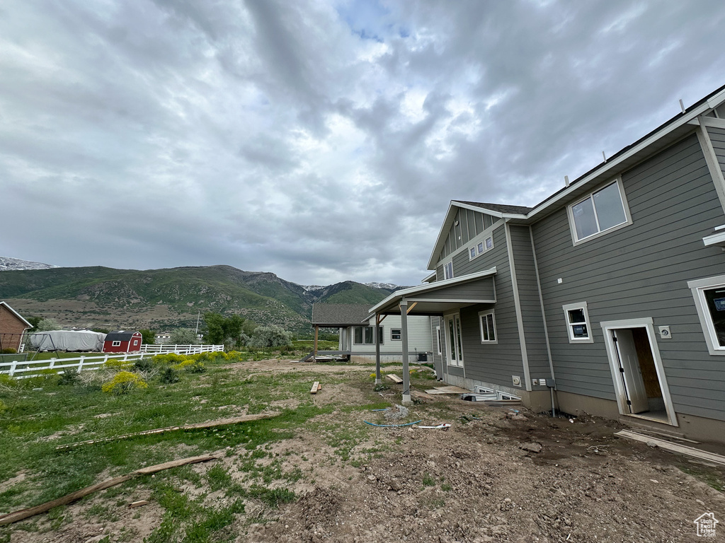 Back of property featuring a mountain view and fence