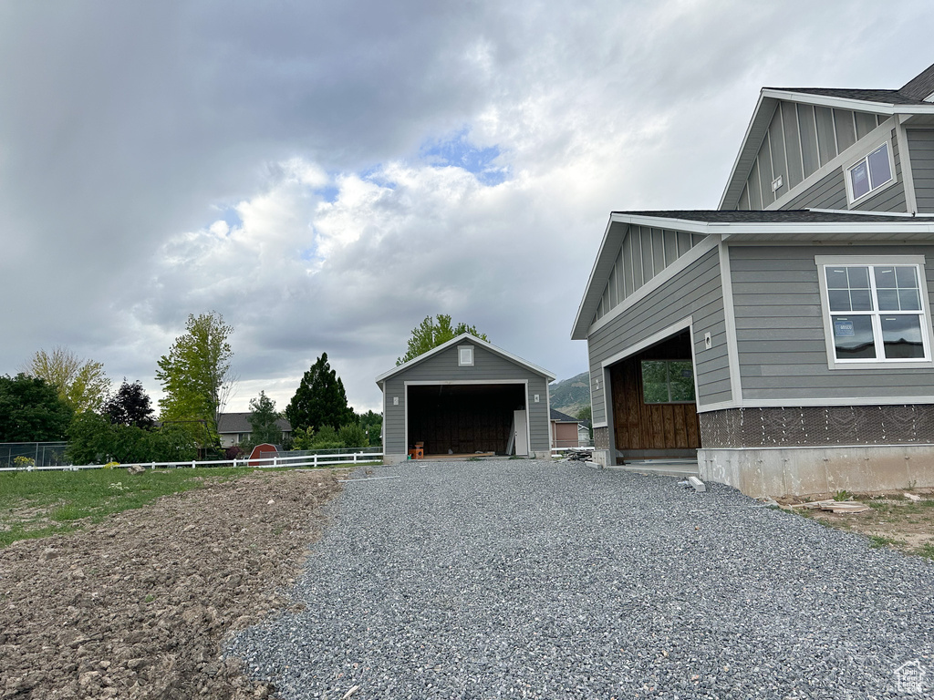 View of home\'s exterior with board and batten siding, an outdoor structure, fence, and a detached garage