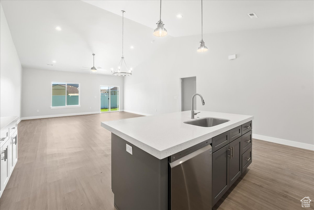 Kitchen with white cabinets, sink, stainless steel dishwasher, a kitchen island with sink, and wood-type flooring