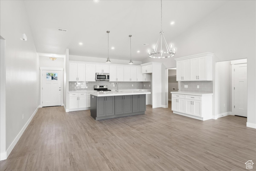 Kitchen featuring backsplash, hardwood / wood-style flooring, and a center island with sink