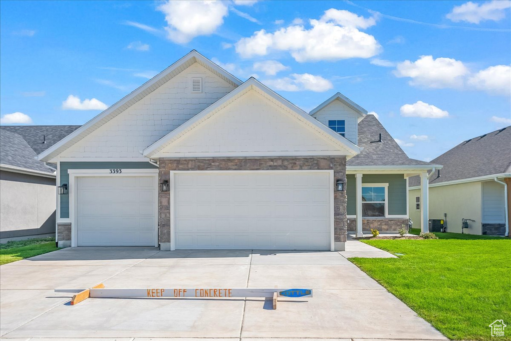 Craftsman-style home with a garage, central AC unit, and a front yard