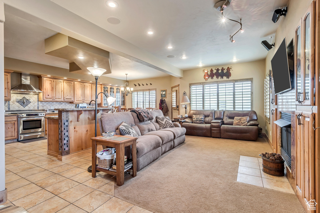 Tiled living room with an inviting chandelier, rail lighting, and a wealth of natural light