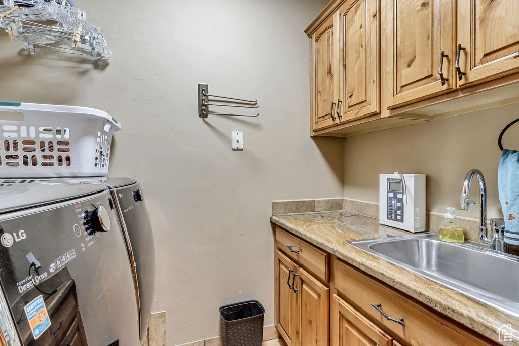 Washroom with sink, washing machine and dryer, and cabinets