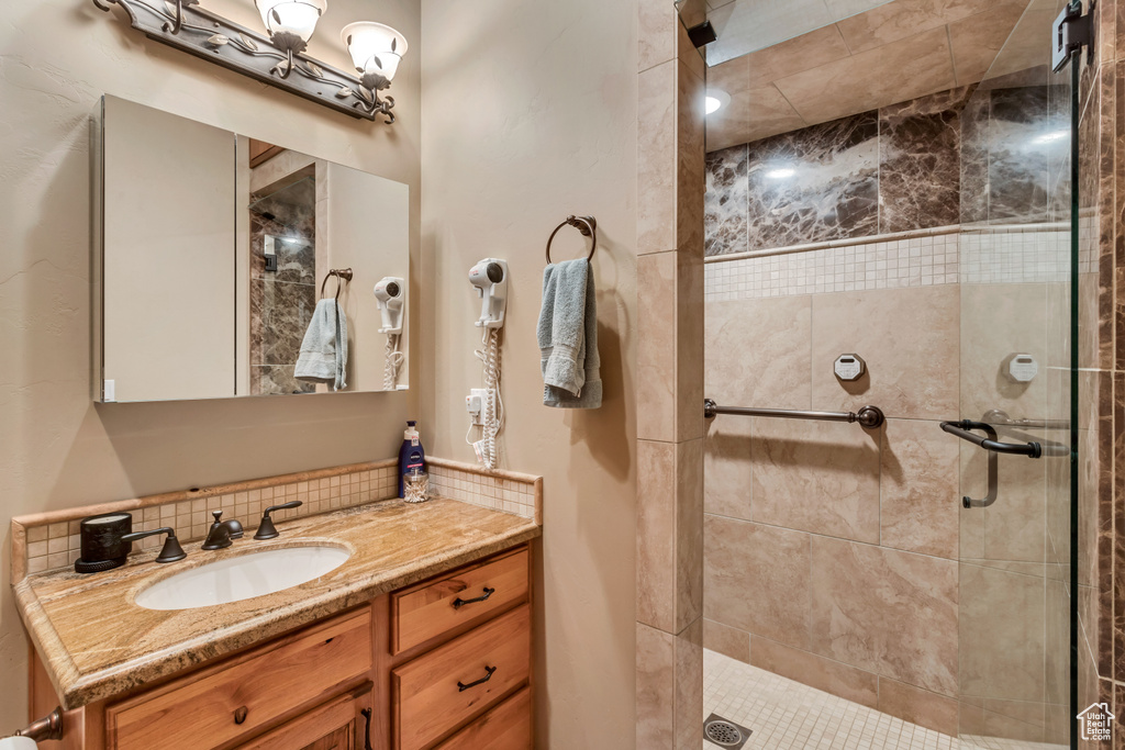 Bathroom featuring vanity, walk in shower, and backsplash