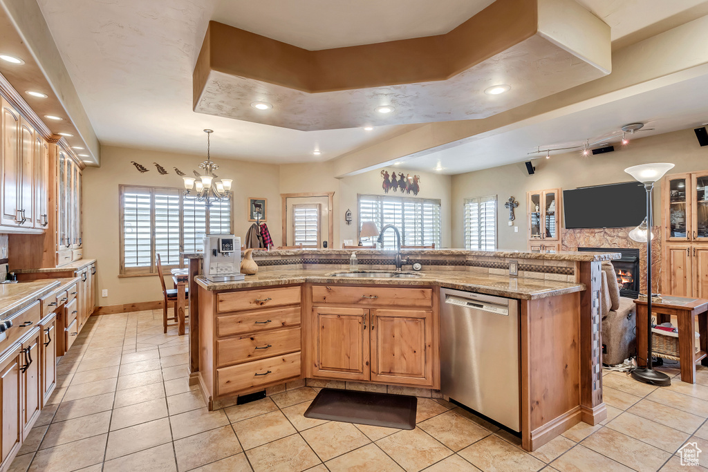 Kitchen featuring plenty of natural light, a stone fireplace, sink, and stainless steel dishwasher