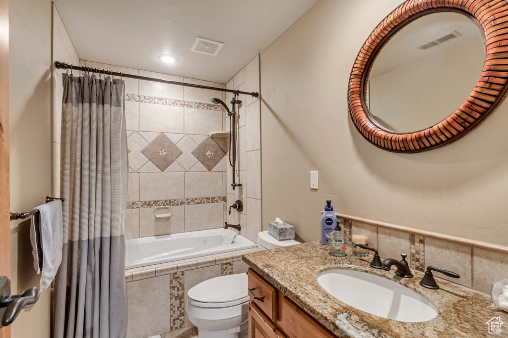 Full bathroom featuring vanity, toilet, and shower / bathtub combination with curtain